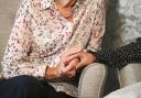 Photo by PA of a care home resident holding hands with her daughter.