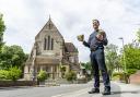 Revd Mike Trotman holding the cracked stone outside St Peter's Church, Parkstone.