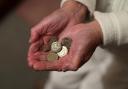 Elderly woman holding pound coins in her hands, in Poole, Dorset.