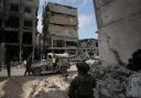 Israeli soldiers take up position next to buildings destroyed by the Israeli military in the Gaza Strip (Leo Correa/AP)