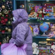 A shopper wearing face mask passes a festive shop display. Photo: PA.