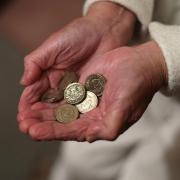 Elderly woman holding pound coins in her hands, in Poole, Dorset.