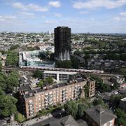 A tube train passes the remains of Grenfell Tower