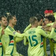 Kieffer Moore (headband) celebrates with his Wales team-mates after opening the scoring against Montenegro (Risto Bozovic/AP)