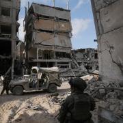 Israeli soldiers take up position next to buildings destroyed by the Israeli military in the Gaza Strip (Leo Correa/AP)