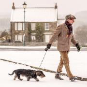 A man walks his dog in fresh snow in the village of Goathland, North York Moors National Park (/PA)