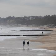 People walk along Bournemouth beach in Dorset as the cold snap continues to grip much of the