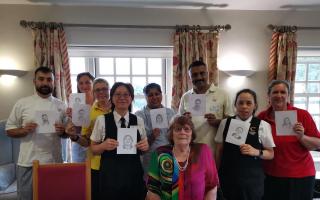 Judith Forster, seated, with some of the 73 Abbey View staff members who she sketched. From left: Mannie, Elisa, Tracey, Simmi, Thushara, George, Bobbi and Sara.